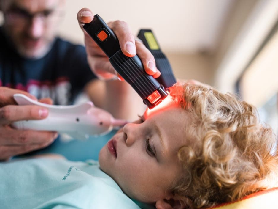 A child lies on a mat while a clinician works beside them.