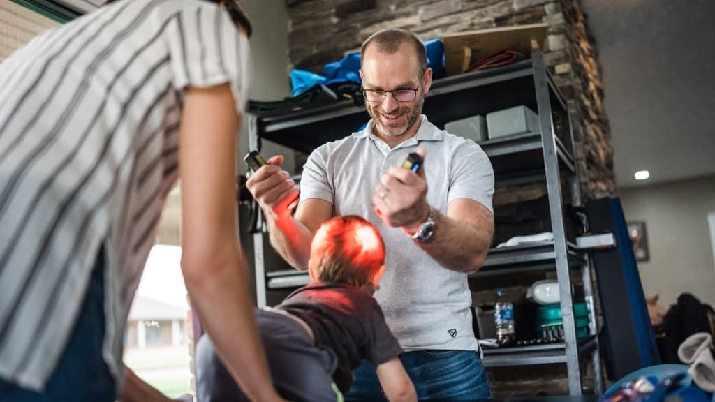 A clinician works with a child in a treatment room at the clinic, another adult beside them.